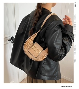Detail of light brown croc-effect crescent bag with gold buckle on a stylish model