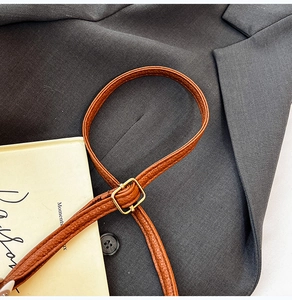 Détail de la bandoulière réglable en cuir marron avec boucle dorée sur le sac à main