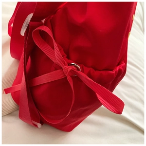 Detailaufnahme einer roten Stickerei-Tasche mit Kordelzug und silbernem Metallring