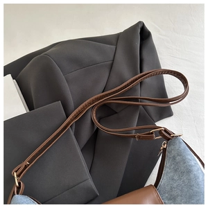 Dettaglio borsa a tracolla retrò in denim blu e pelle marrone con cuciture rifinite