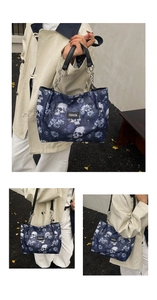 Close-up of tote bag with skull floral print, leather handles and fashion label detail