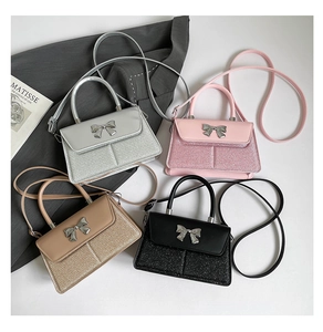 Detail of glitter mini square bags with metallic bow decoration in four trendy colors