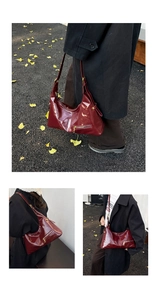 Detail of dark red oil-wax leather hobo bag with a gold zipper and vintage texture