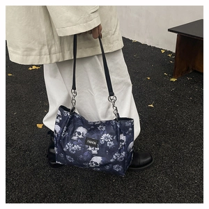 Detail of street-style tote bag featuring skull and floral print with metallic chain strap
