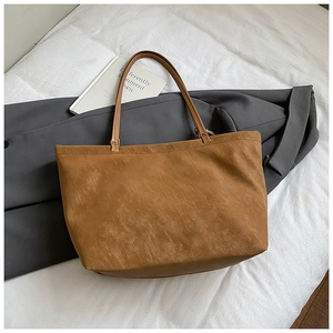 Macro detail of the brown leather tote bag texture and slender shoulder strap on soft bedding