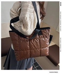 Side view of a brown quilted puffer tote bag with black straps on a female model