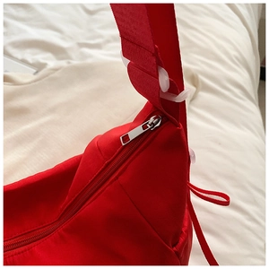 Detailaufnahme der roten Nylontasche mit silbernem Reißverschluss und verstellbarer Schnalle