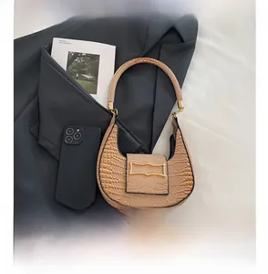 Detailed view of crocodile pattern hobo bag with gold buckle next to a phone for size