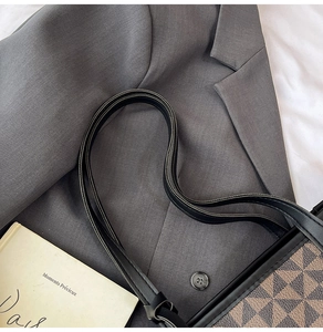 Macro detail of brown geometric print tote bag with black leather shoulder strap