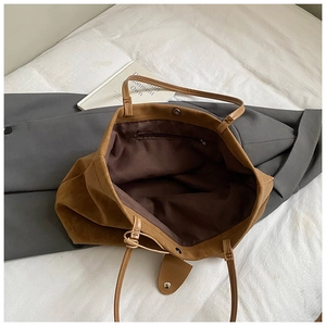 Detail view of large brown tote bag showing magnetic clasp and internal zipper pocket