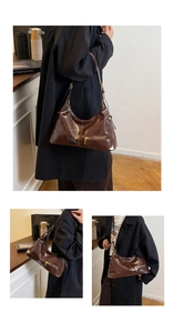 Detail of a dark brown patent leather hobo bag with a gold metal zipper and slim strap