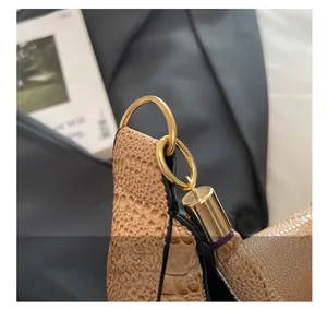 Detail of golden ring hardware and faux crocodile texture on light brown PU leather bag