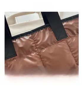 Close-up of caramel quilted puffer tote bag with reinforced stitching and black straps