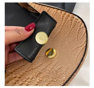Macro view of gold magnetic closure on brown crocodile pattern PU leather shoulder bag