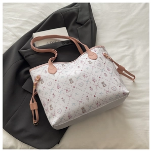 Detail of white tote bag with pink bear patterns and slim handles on a bed