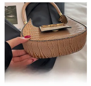 Close-up of brown crocodile pattern shoulder bag with golden twist lock detail
