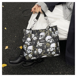 Detail of dark skull and floral print tote bag on street with silver chain handle