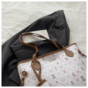 Detail of white tote bag with cartoon bear patterns and reinforced brown leather straps