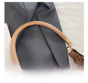 Macro detail of brown crocodile textured handle and gold D-ring hardware on handbag