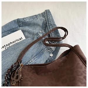 Detail of brown leopard print hobo bag featuring twin-G charm and woven rope accent