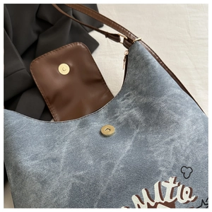 Dettaglio della borsa hobo in denim vintage con stampa artistica e fibbia in pelle marrone