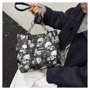 Detail of black tote bag with white skull and floral pattern featuring metal chain handles