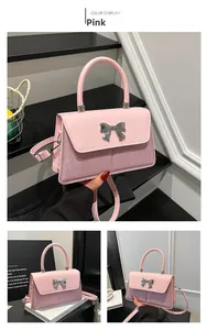 Detail of pink sequin crossbody bag with silver metal bow buckle and smooth texture