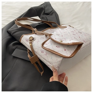 Close-up of white tote bag with brown leather pocket and gold snap on a suit jacket