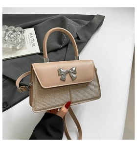 Detail of beige bow shoulder bag with silver metal accent and textured glitter finish