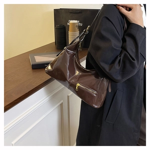 Macro detail of glossy dark brown patent leather hobo bag with sleek metal zipper textures