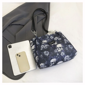 Detail of gothic skull print tote bag with silver chain strap and fashion label