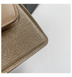 Detail of champagne gold sequin woven fabric and precise stitching on beige leather bag