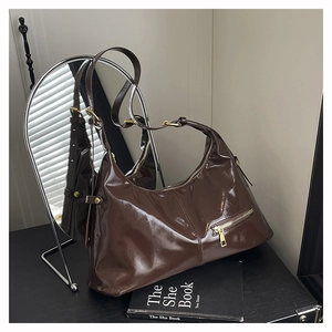 Detail of glossy brown leather tote bag with gold zipper pocket on silver mirror backdrop