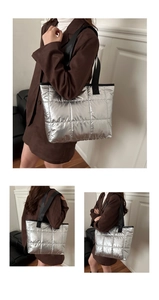 Detailed view of large quilted silver tote bag with black straps and metallic finish