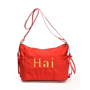Red canvas tote bag with gold Hai embroidery and adjustable shoulder straps