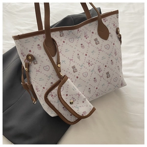 Detail of floral tote bag with matching pouch and brown leather handles on white bedding