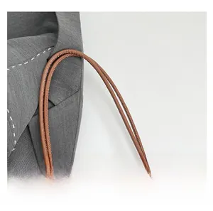 Close-up of brown faux leather handle with fine stitching on wool fabric tote bag