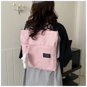 Pink canvas tote bag detail featuring plush bunny pendant and black logo pocket