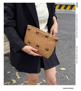 Brown quilted nylon clutch with black bow embroidery details shown in outdoor street style