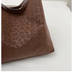 Close-up of leopard print texture on brown faux leather tote bag with stitch detail