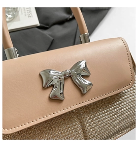 Macro detail of beige handbag featuring a silver mirror bow buckle and woven texture