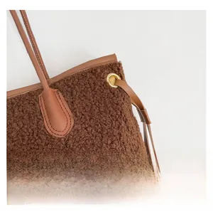 Detail of brown faux shearling tote bag with leather straps and gold metal eyelets