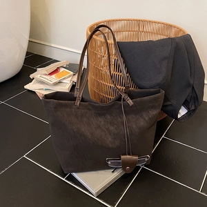 Brown matte leather tote bag with unique glasses holder charm on marble floor