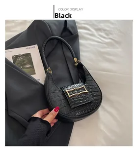 Detailed view of black crocodile pattern crescent bag with golden geometric clasp
