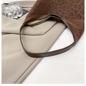 Detail of leopard print tote bag with brown leather strap and soft suede texture