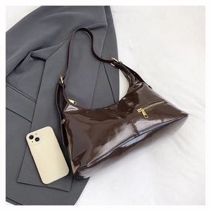 Detail of dark brown hobo shoulder bag with glossy leather texture and golden hardware buckle