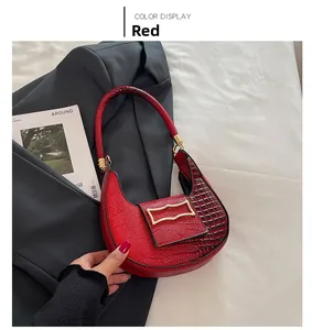 Detail of red crescent moon shoulder bag with crocodile pattern and gold buckle