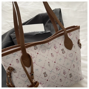 Detail of cartoon bear print tote bag with brown handles and side rivet accents
