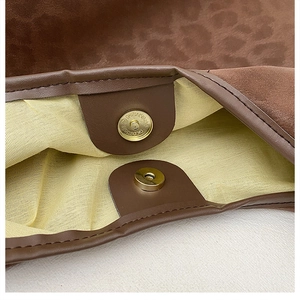 Detail of the magnetic snap closure on the leopard texture tote bag with brown suede trim