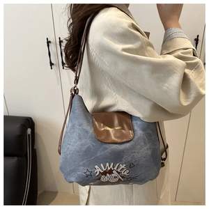 Dettaglio borsa hobo in denim azzurro con tracolla in pelle marrone e scritta tidal dorata